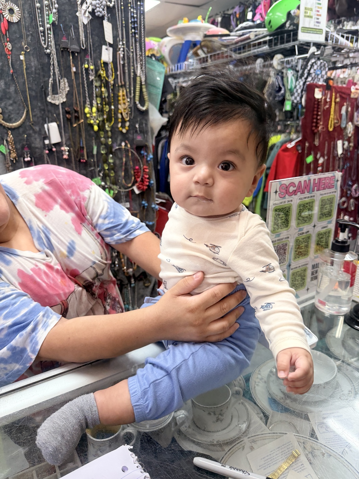A baby being held by a caregiver at Magical New Beginnings Thrift Shop