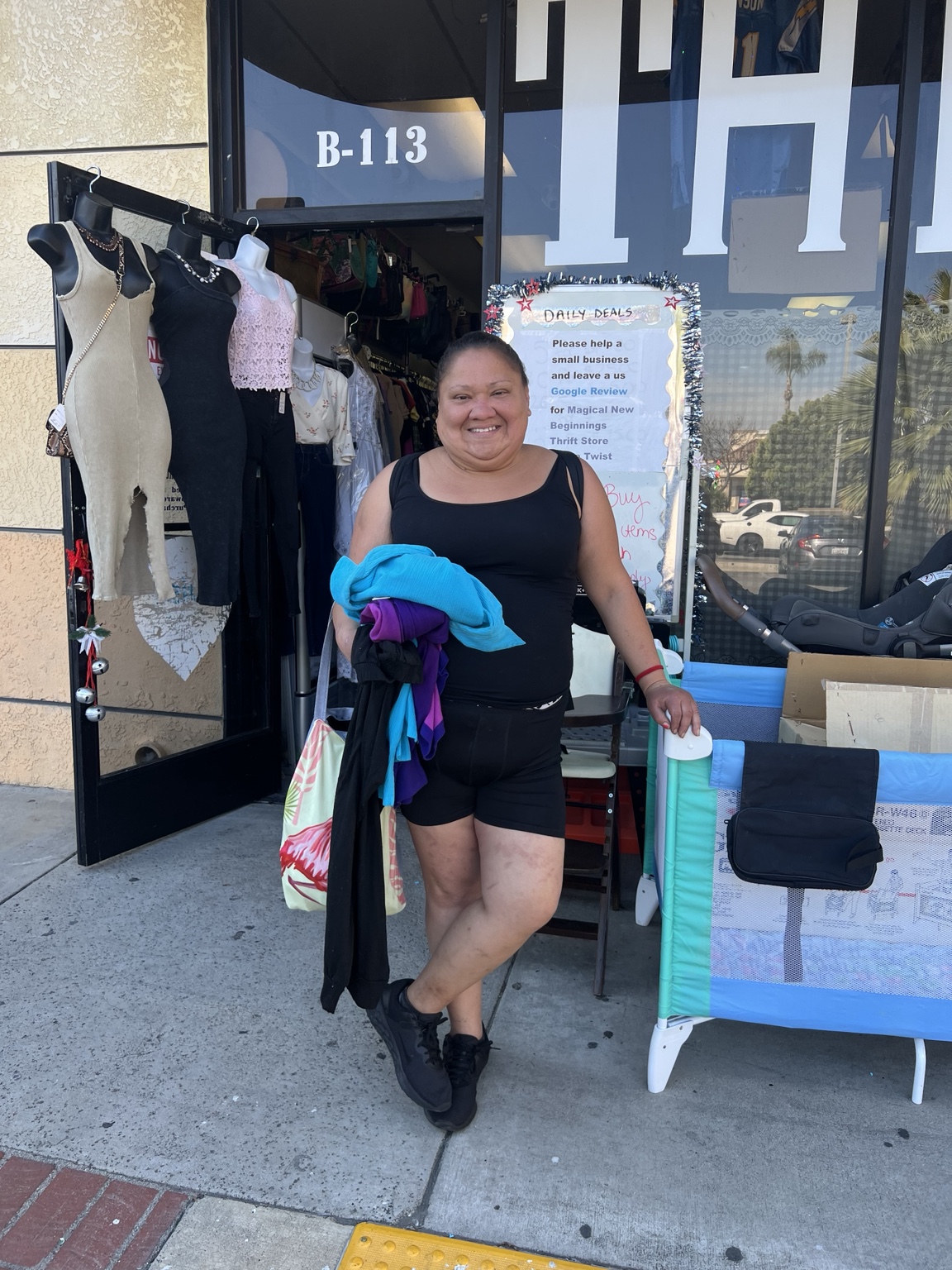 A community member outside the thrift shop holding clothing