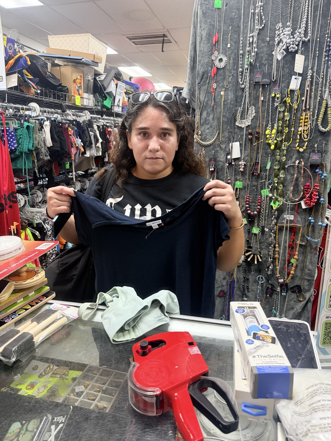 A community member holding up clothing at Magical New Beginnings Thrift Shop